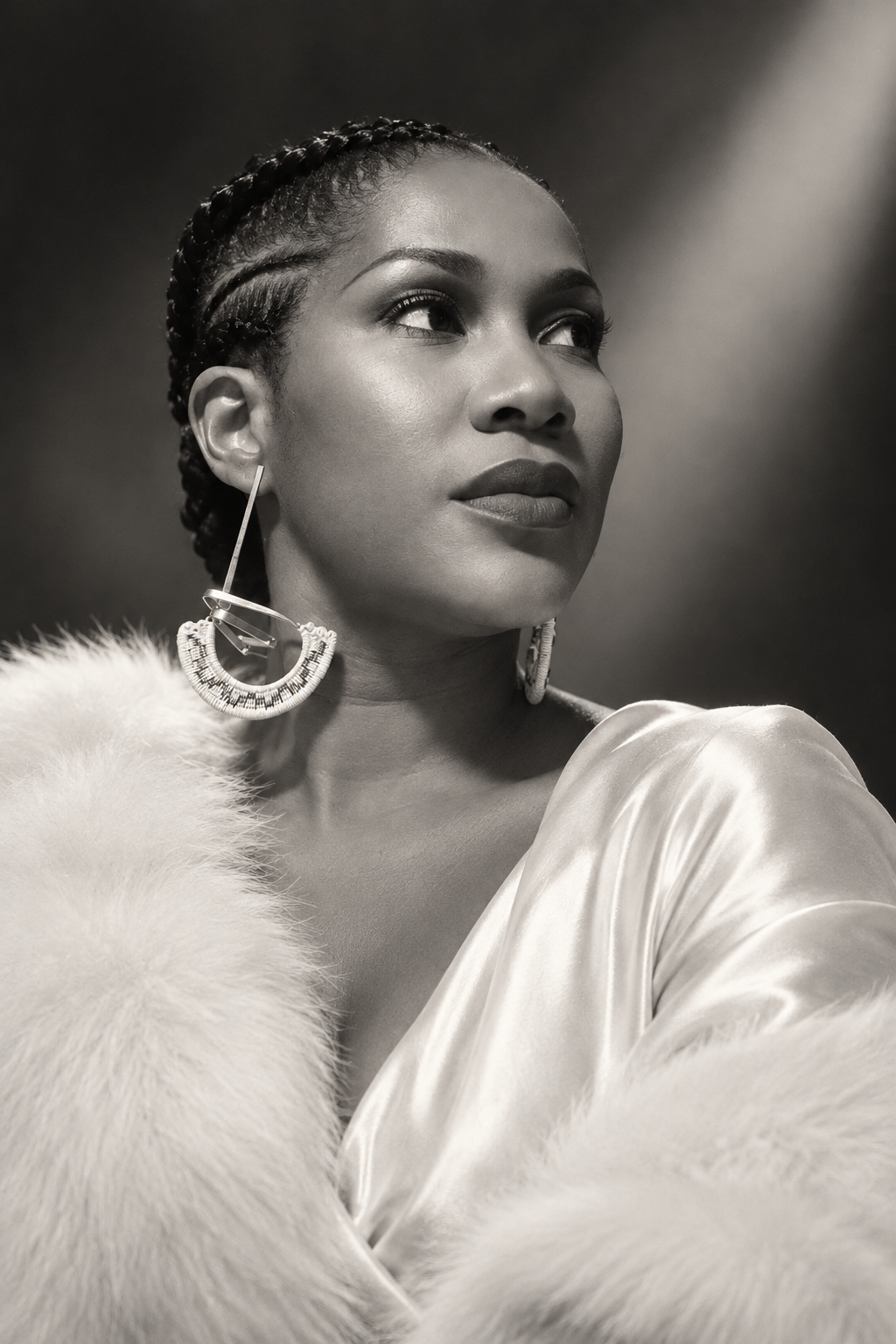 Black and white birthday portrait of Stephanie Linus looking ahead, wearing statement earrings and a feather-trimmed outfit.