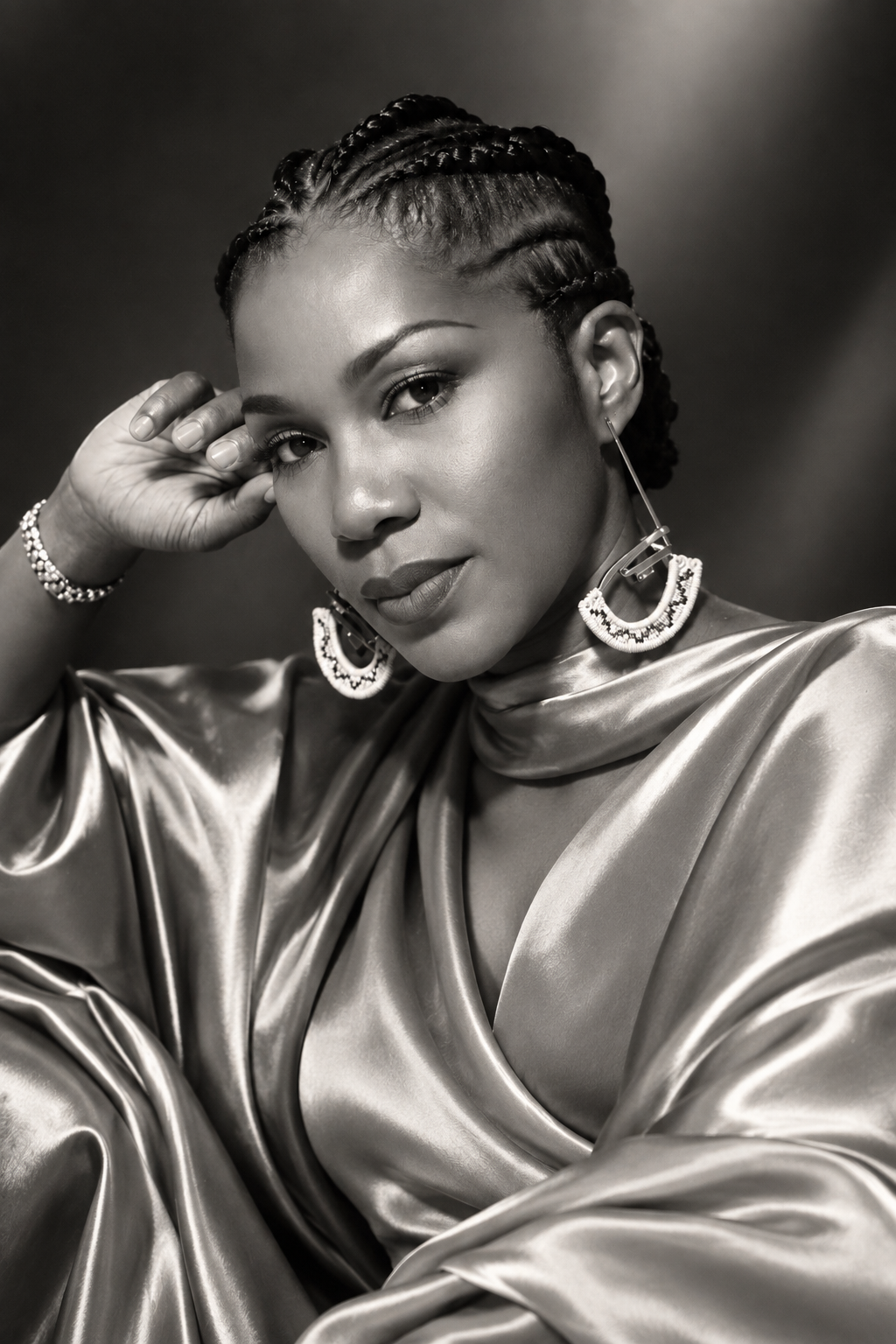 Black and white birthday portrait of Stephanie Linus in a satin outfit, resting her hand beside her face.