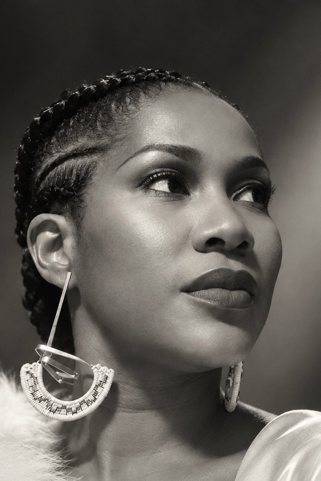 Black and white portrait of Stephanie Linus with braided hair and statement earrings.