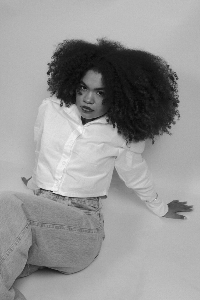 Black woman wearing a white button-down shirt with jeans in a monochrome portrait