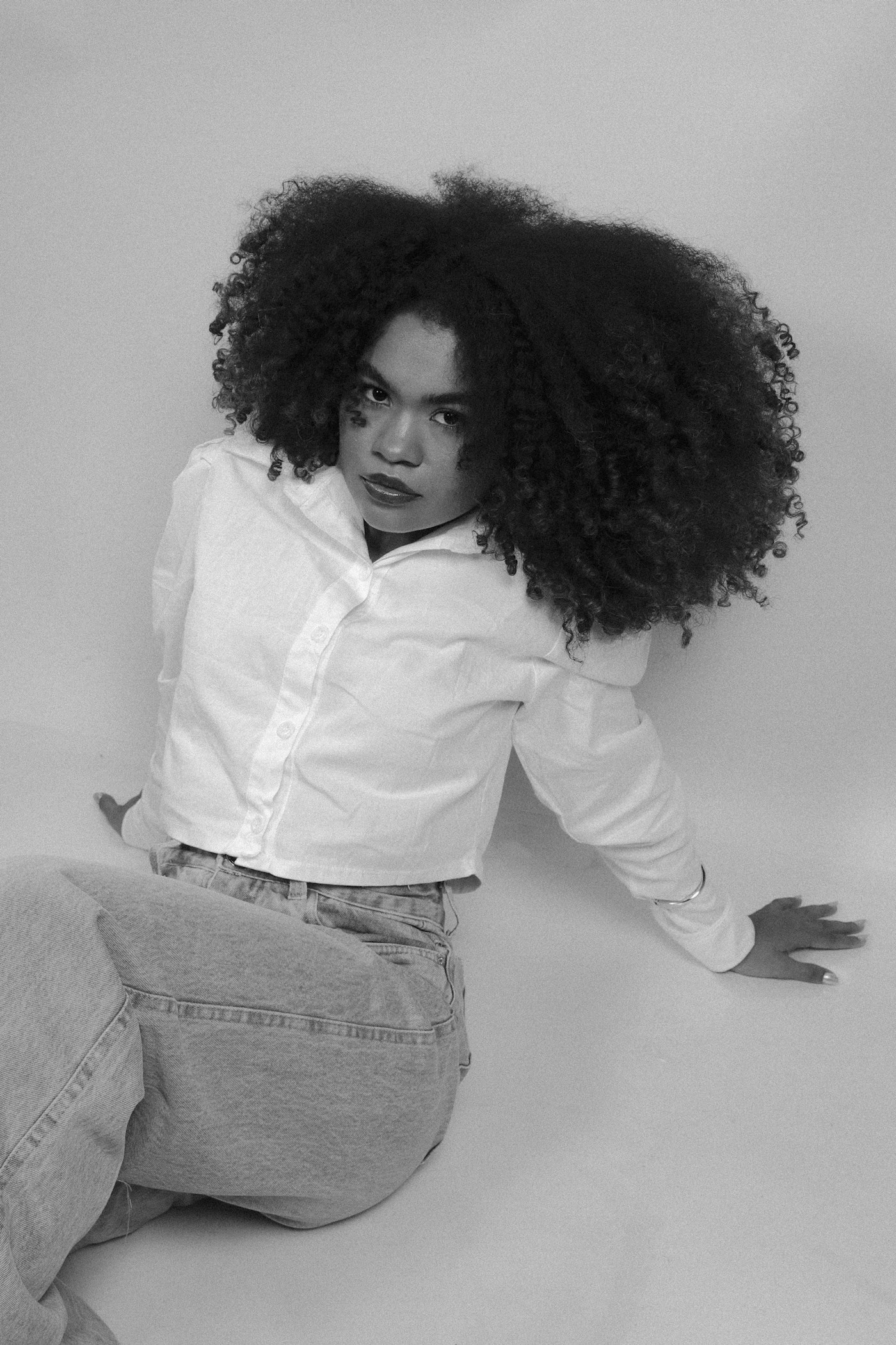 Black woman wearing a white button-down shirt with jeans in a monochrome portrait