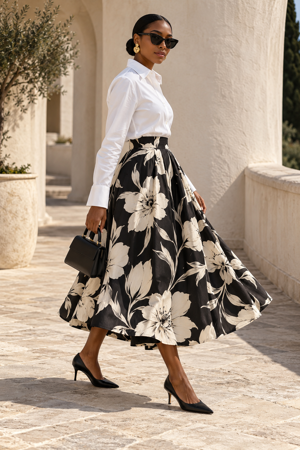 Black woman wearing a white shirt tucked into a black and ivory floral midi skirt